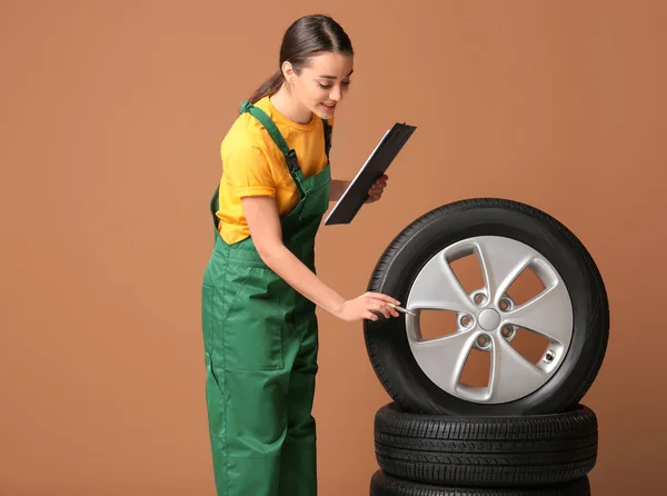 Feminino mecânico em uniforme com pneus de carro e área de transferência em fundo de cor — Fotografia de Stock