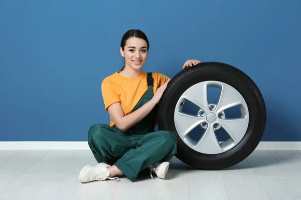 배경에 색 벽에 자동차 타이어와 유니폼에 여성 정비공 — 스톡 사진