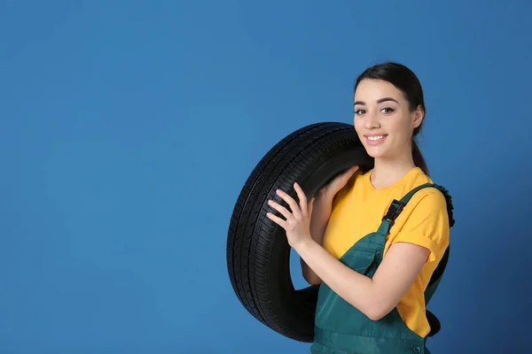 Vrouwelijke monteur in uniform met auto band op kleur achtergrond — Stockfoto