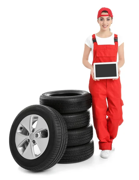 Mecânico feminino em uniforme com pneus de carro e tablet no fundo branco — Fotografia de Stock