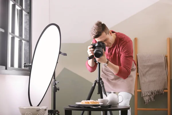 Молодой человек фотографирует еду в фотостудии — стоковое фото