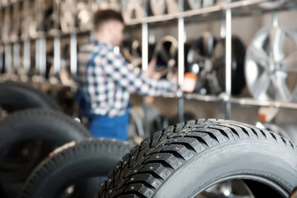 Opony samochodowe i niewyraźne mechanika mężczyzna na tle w centrum obsługi samochodów — Zdjęcie stockowe