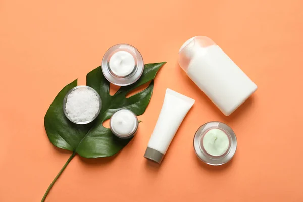 Produtos cosméticos diferentes do cuidado da pele com folha verde no fundo da cor, vista superior — Fotografia de Stock