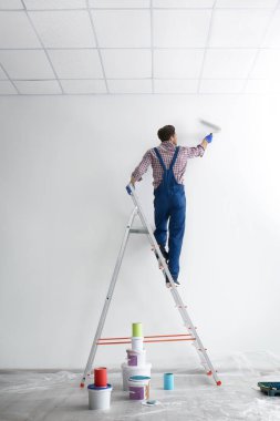 Boş oda içinde roller ile erkek dekoratör boyama duvar