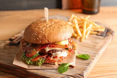 Pastırmalı lezzetli hamburger ve tahtanın üzerinde patates kızartması.