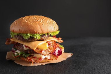 Koyu arka plan karşı masada pastırma ile lezzetli duble burger