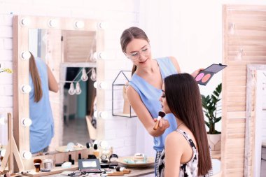 Profesyonel visage sanatçı salonda kadının yüzünde makyaj uygulamak