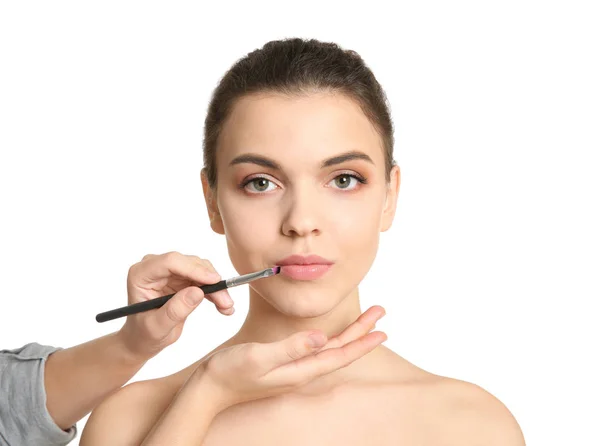 Visage konstnären tillämpa makeup på kvinnans ansikte mot vit bakgrund. Professionella kosmetiska produkter — Stockfoto