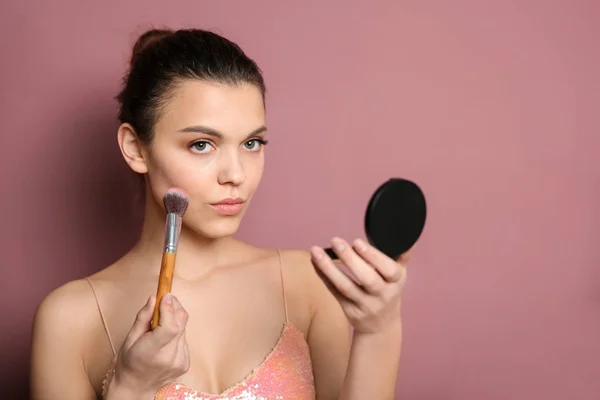 Ung kvinna tillämpa makeup på färgbakgrund. Professionella kosmetiska produkter — Stockfoto