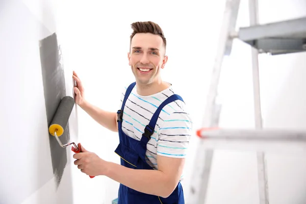 Jovem macho decorador parede de pintura no quarto — Fotografia de Stock