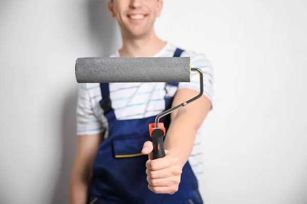 Young male decorator with paint roller on white background — Stock Photo, Image