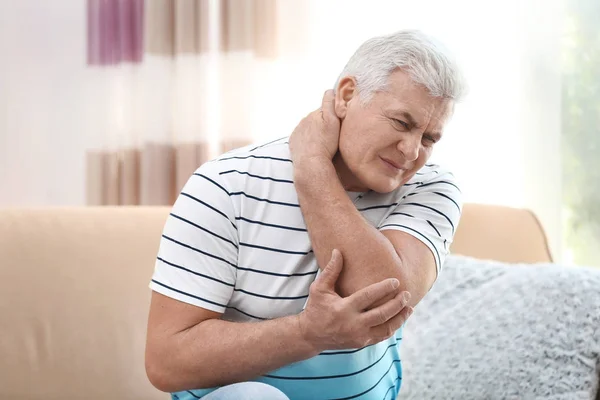 Mature man suffering from neck pain at home — Stock Photo, Image