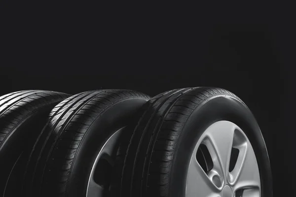 Neumáticos de coche nuevos con llantas en fondo negro, primer plano —  Fotos de Stock