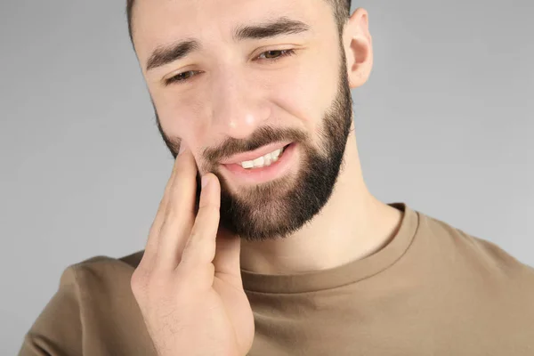 Jeune homme souffrant de maux de dents sur fond clair — Photo