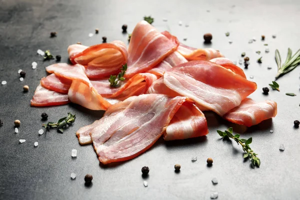 Raw bacon rashers on grey background