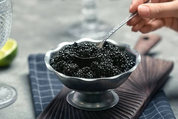 Mulher tomando colher de caviar preto da tigela, close-up — Fotografia de Stock