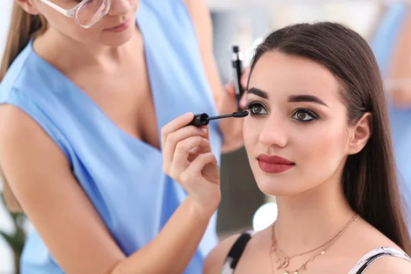 Artista de visagem profissional aplicando maquiagem no rosto da mulher no salão — Fotografia de Stock