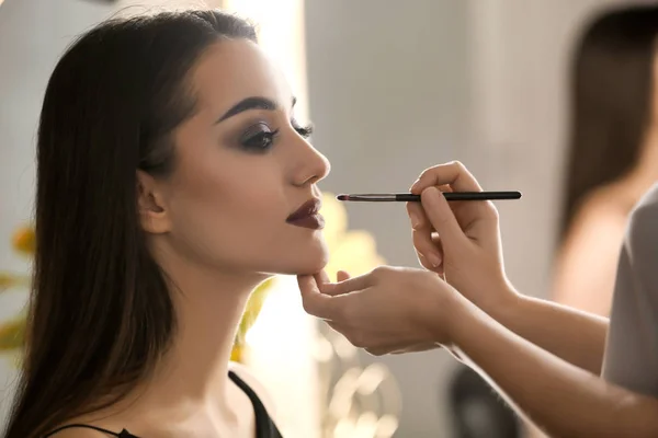 Artista de rostro profesional aplicando maquillaje en la cara de la mujer en el salón — Foto de Stock