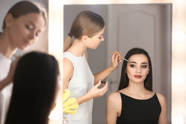 Artista de visagem profissional aplicando maquiagem no rosto da mulher no salão — Fotografia de Stock