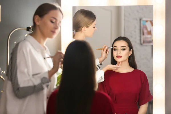 Profesyonel visage sanatçı salonda kadının yüzünde makyaj uygulamak — Stok fotoğraf