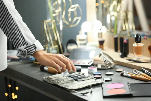 Professional makeup artist near dressing table with decorative cosmetics in beauty salon — Stock Photo, Image