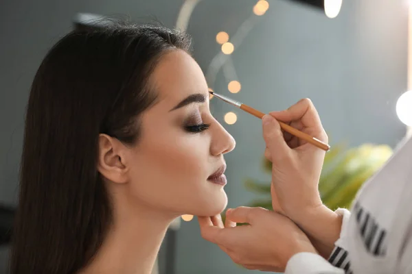 Artista de rostro profesional aplicando maquillaje en la cara de la mujer en el salón — Foto de Stock