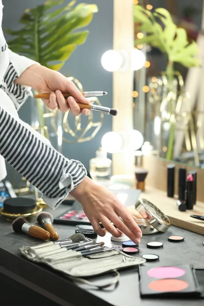 Professional makeup artist near dressing table with decorative cosmetics in beauty salon — Stock Photo, Image