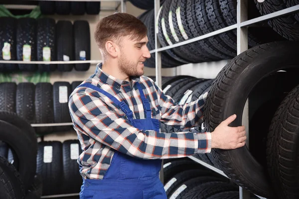 Mladý muž mechanik s auto pneumatiky v automobilovém servisní centrum — Stock fotografie