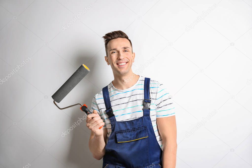 Young male decorator with paint roller on white background