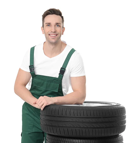 Joven mecánico en uniforme con neumáticos de coche sobre fondo blanco —  Fotos de Stock