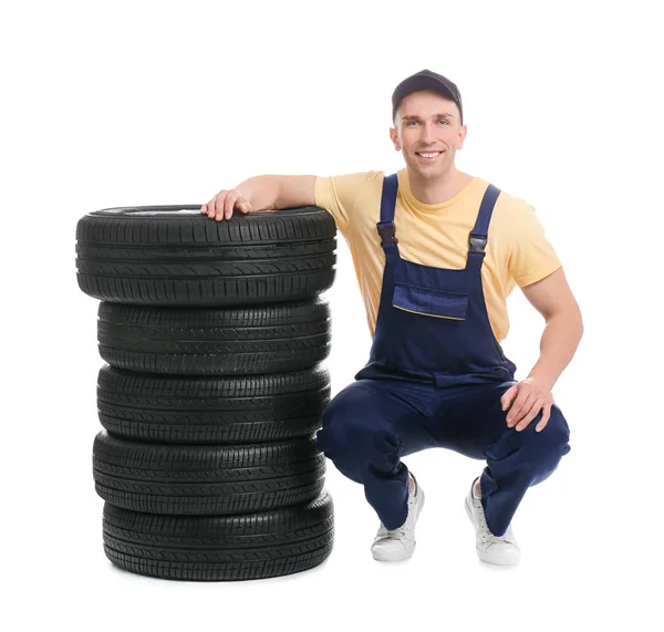 Mecánico masculino con neumáticos de coche sobre fondo blanco — Foto de Stock