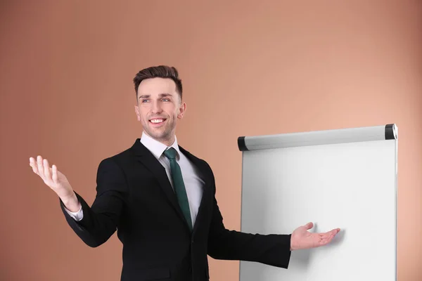 Pelatih bisnis muda dekat flip chart pada latar belakang warna — Stok Foto
