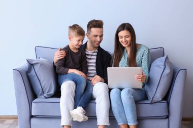 Kanepede kapalı oturan dizüstü bilgisayar ile mutlu aile