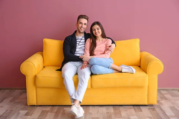 Šťastný mladý pár sedí na pohovce, uvnitř — Stock fotografie