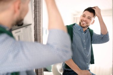 Olgun bir adam aynaya bakıyor.