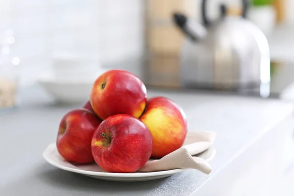 Тарелка со спелыми красными яблоками на столе — стоковое фото