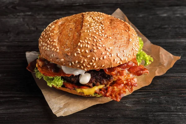 Hambúrguer saboroso com bacon na mesa de madeira — Fotografia de Stock
