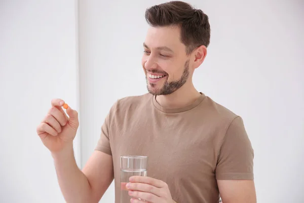 Young man taking vitamin indoors