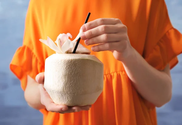 Femme avec boisson fraîche de noix de coco en noix sur fond de couleur, gros plan — Photo