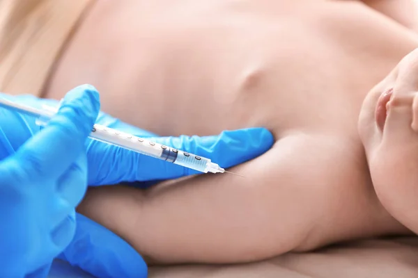 Врач вакцинирует ребенка в клинике, крупным планом — стоковое фото