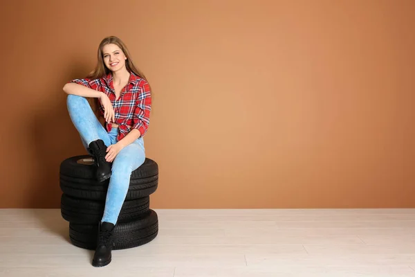 Genç kadın renk duvar arka plan üzerinde araba lastikleri ile baştan çıkarıcı kıyafeti — Stok fotoğraf