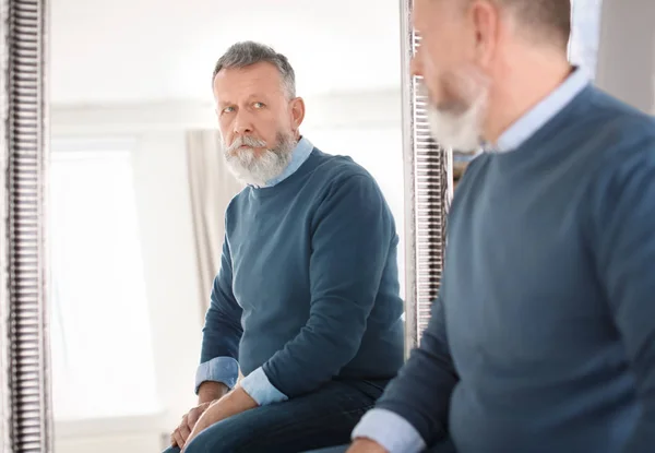 Mature man looking in mirror at home — Stock Photo, Image