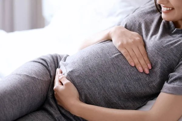 Młoda kobieta w ciąży, leżąc na łóżku w domu — Zdjęcie stockowe
