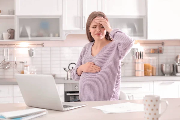 Молодая беременная женщина, страдающая головной болью в домашнем офисе — стоковое фото