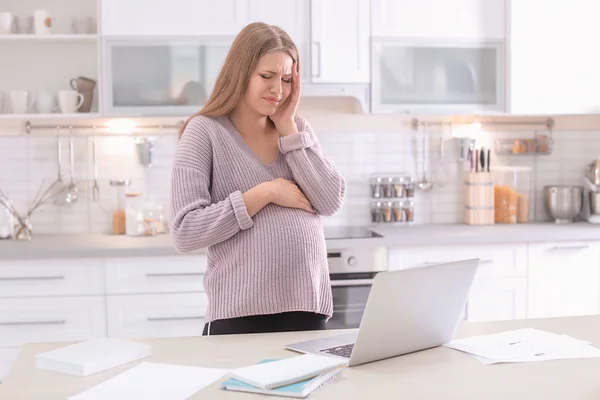 Молодая беременная женщина, страдающая головной болью в домашнем офисе — стоковое фото