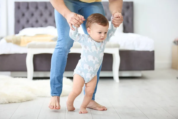 Baby taking first steps with father 's help at home — стоковое фото