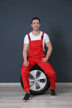 Otomobil lastiği karanlık duvarının yakınında oturan üniforma içinde genç makinist