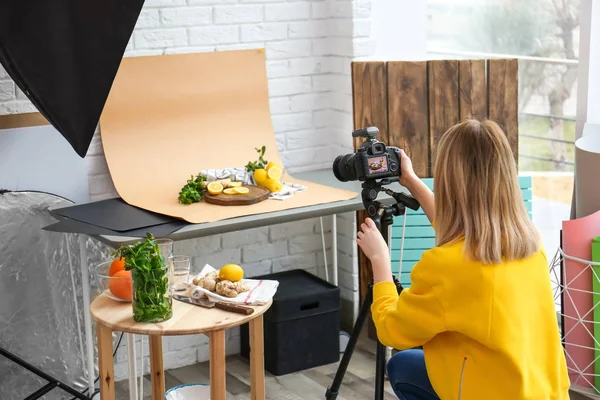 Молода жінка фотографує лимони, м'ята та імбир у професійній студії. Продовольча фотографія — стокове фото