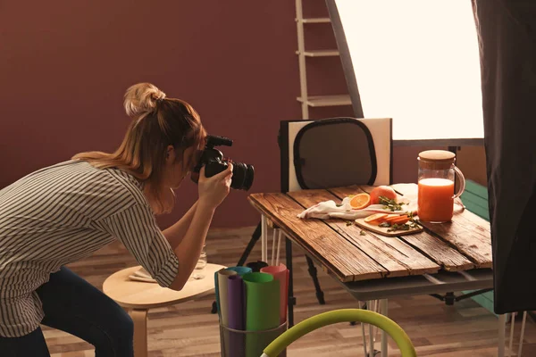 Woman taking picture of oranges and jug with juice on table. Food photography — Stock Photo, Image