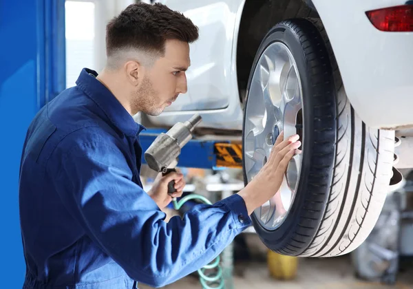 Jovem roda de mudança mecânica no serviço de pneus — Fotografia de Stock